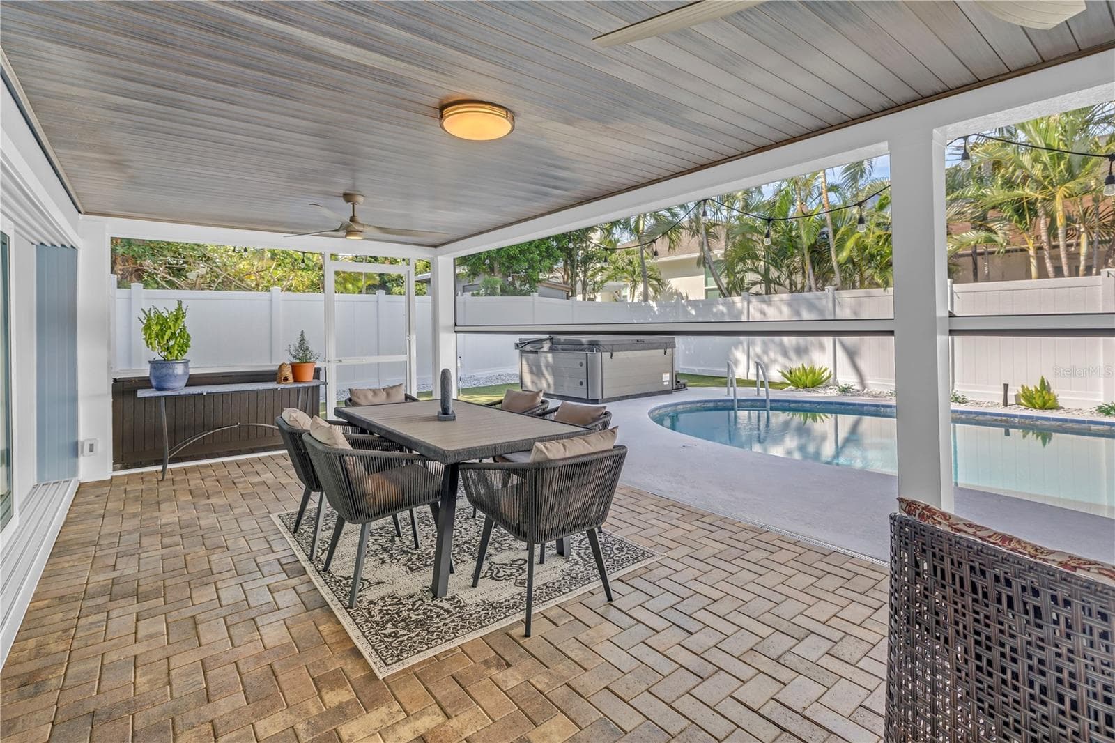 Paved patio with bead board ceiling for your outdoor Dining room with pool and HOT TUB beyond. Remote screens at half mast! - 1114 2ND AVE S, TIERRA VERDE