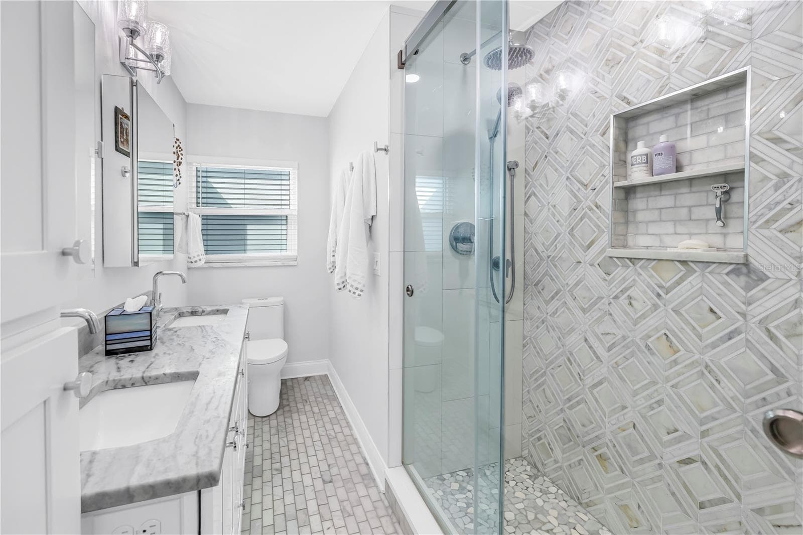 Primary bath with designer shower with spa stones and Art Deco influenced sand and sea aesthetic and built- in shower niche. - 1114 2ND AVE S, TIERRA VERDE