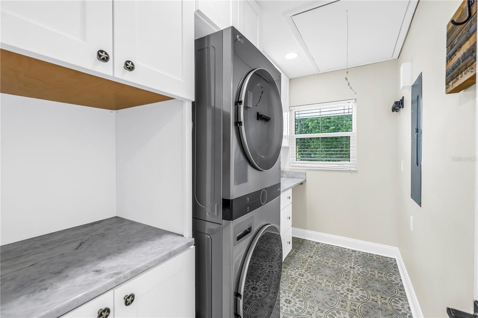 Oversized laundry room with Shaker cabinetry, quartz countertops (all match kitchen), utility sink, storage and FULL size stackable LG ThinQ high efficiency washer and dryer. - 1114 2ND AVE S, TIERRA VERDE