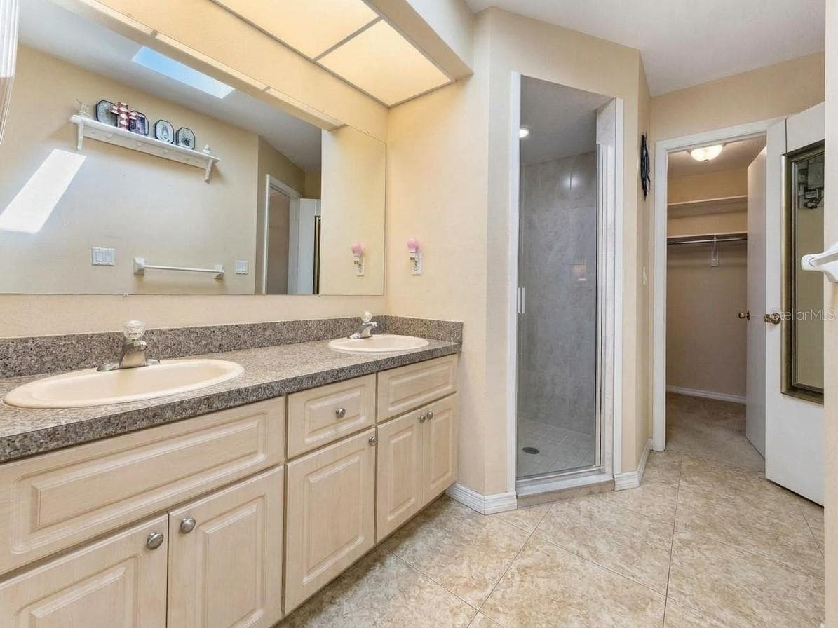 Primary Bathroom | Additional view of the primary bathroom showcasing the vanity, storage, and adjoining primary suite. - 23088 GRAY AVE, PORT CHARLOTTE