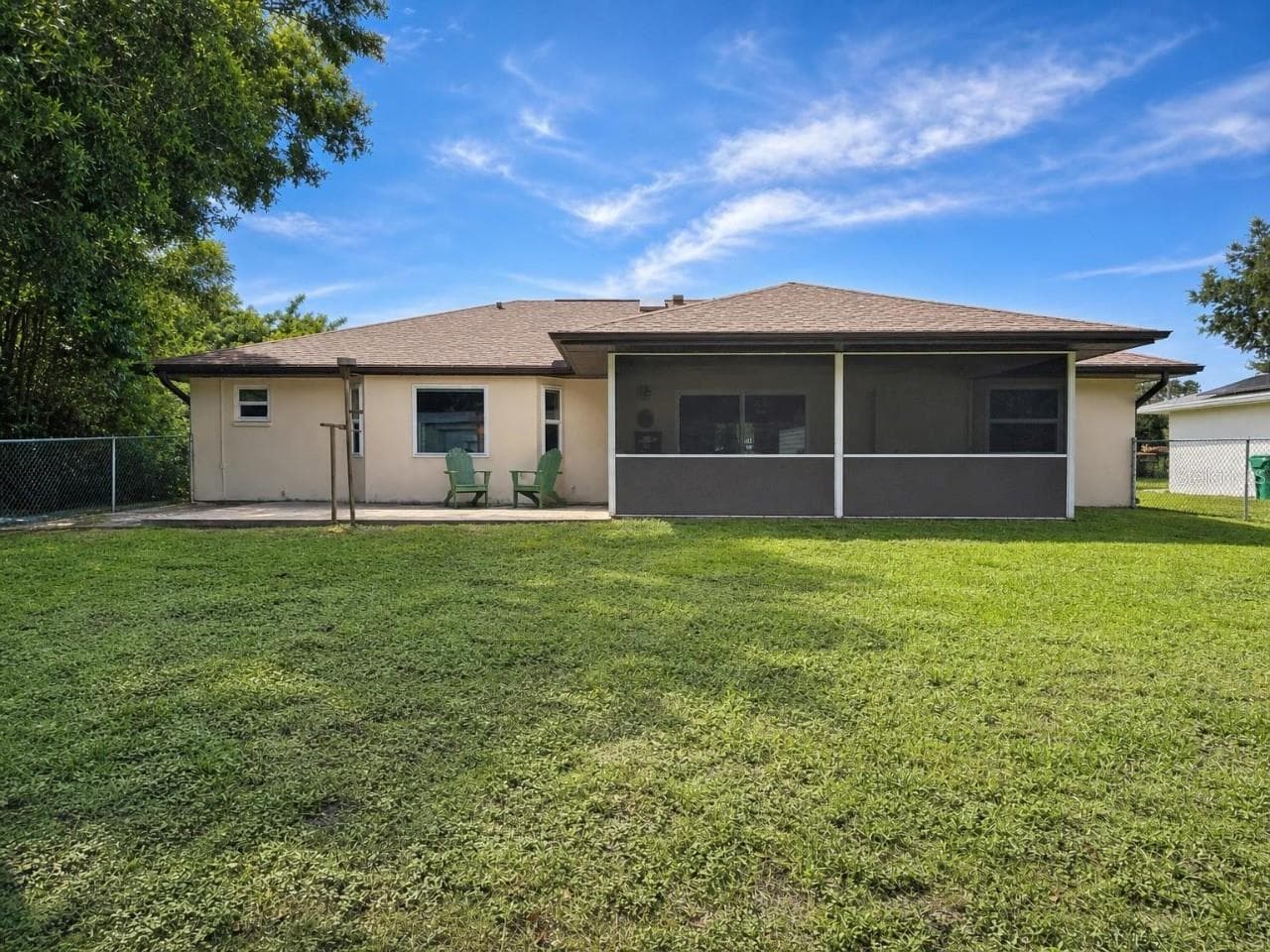 Rear Exterior | Rear view showcasing the screened lanai, extended paver patio, and generous fenced backyard. - 23088 GRAY AVE, PORT CHARLOTTE
