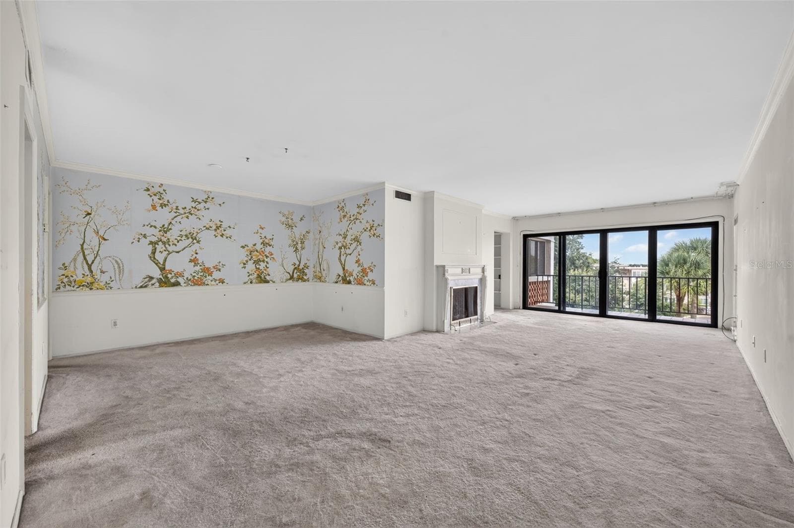 A spacious, light-filled living and dining area features a classic fireplace, walls of glass, and beautiful treetop views, offering endless possibilities to create a stunning modern retreat. - 100 S INTERLACHEN AVE #401, WINTER PARK