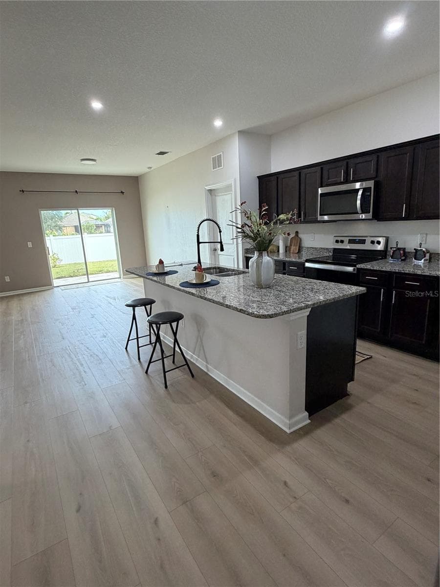 New 9X60 Flooring in Large Kitchen features Oversized Granite Island Upgraded faucet and walk in pantry - 1261 ANCHOR BEND DR, RUSKIN