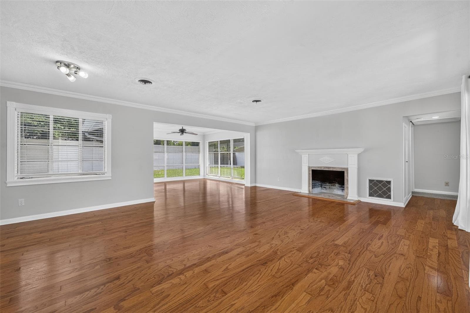 Living & Dining Area — Spacious combined living and dining area with hardwood floors, crown molding, fireplace, detailed millwork and abundant natural light from large-format windows. - 200 SENECA TRL, MAITLAND