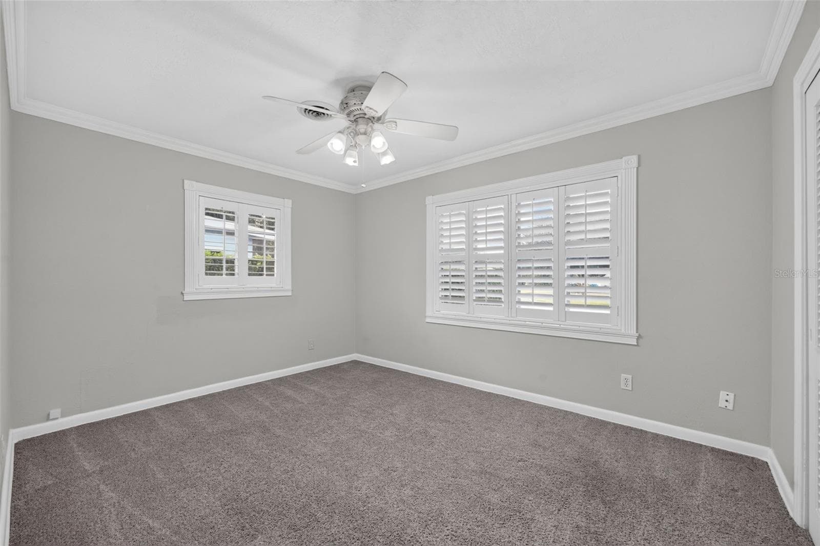 Primary Bedroom — Ample-sized primary bedroom positioned at the rear of the home with neutral carpeting, crown molding and custom interior shutters. - 200 SENECA TRL, MAITLAND