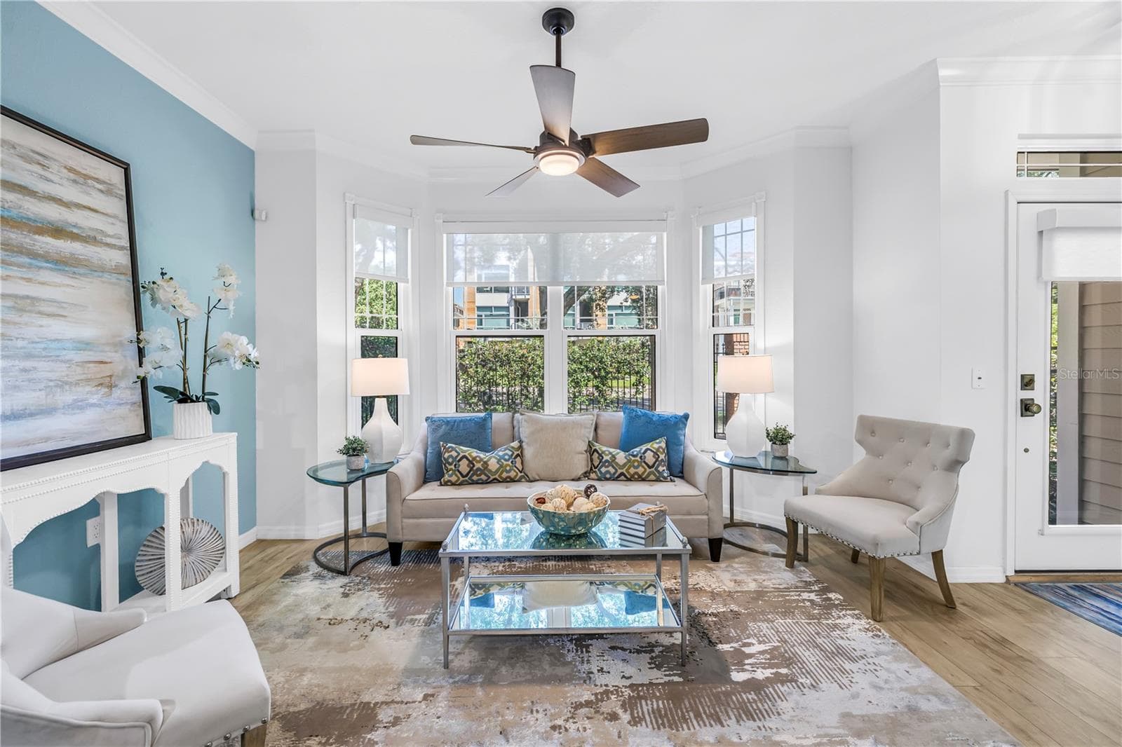 Bright and inviting living room features a bay window, luxury vinyl plank flooring and remote-controlled sun shades - 350 2ND ST N #6, ST PETERSBURG