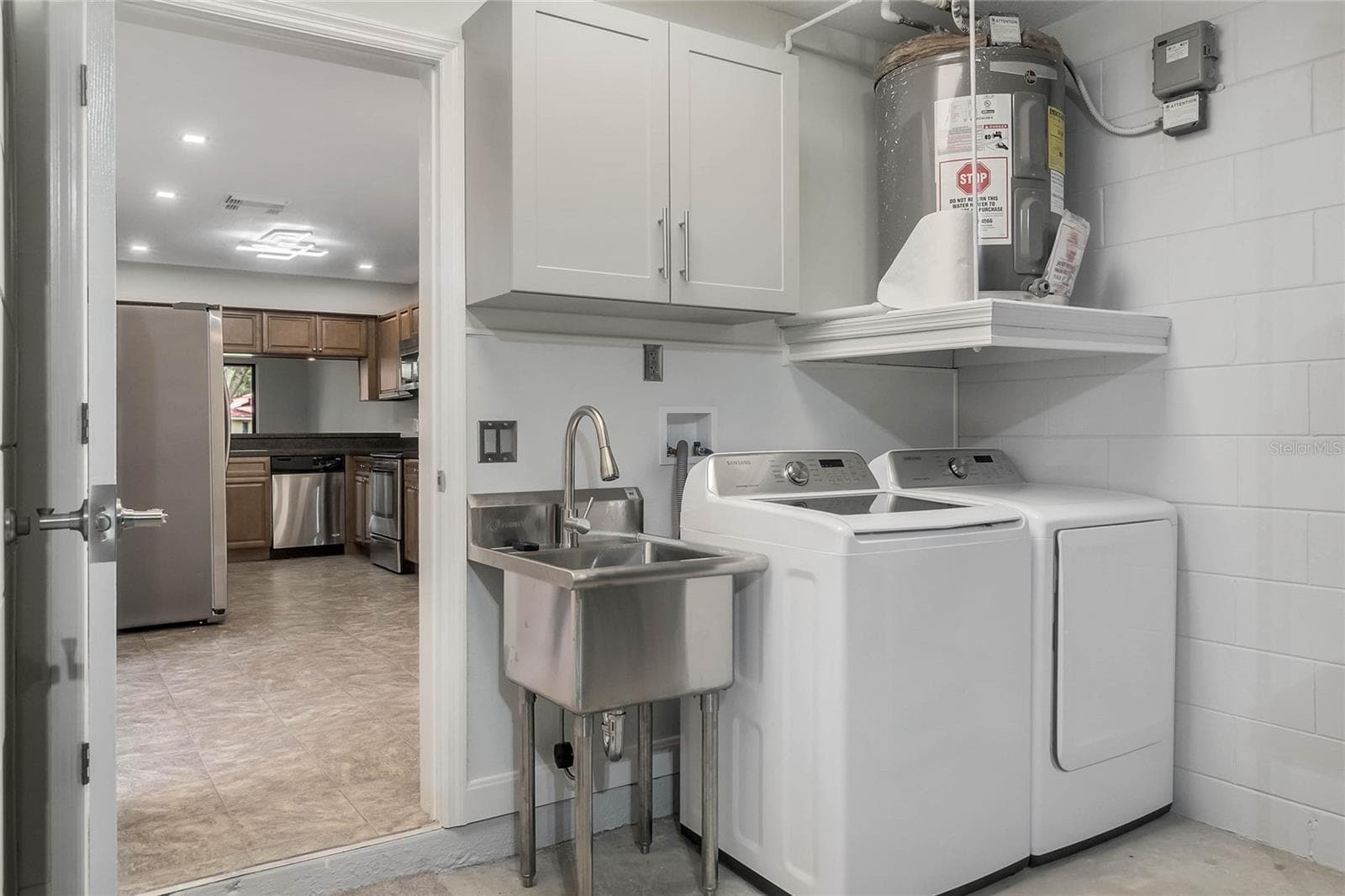 Garage laundry area with washer and dryer space and a utility sink for added convenience. - 8235 AMBROSE COVE WAY, ORLANDO