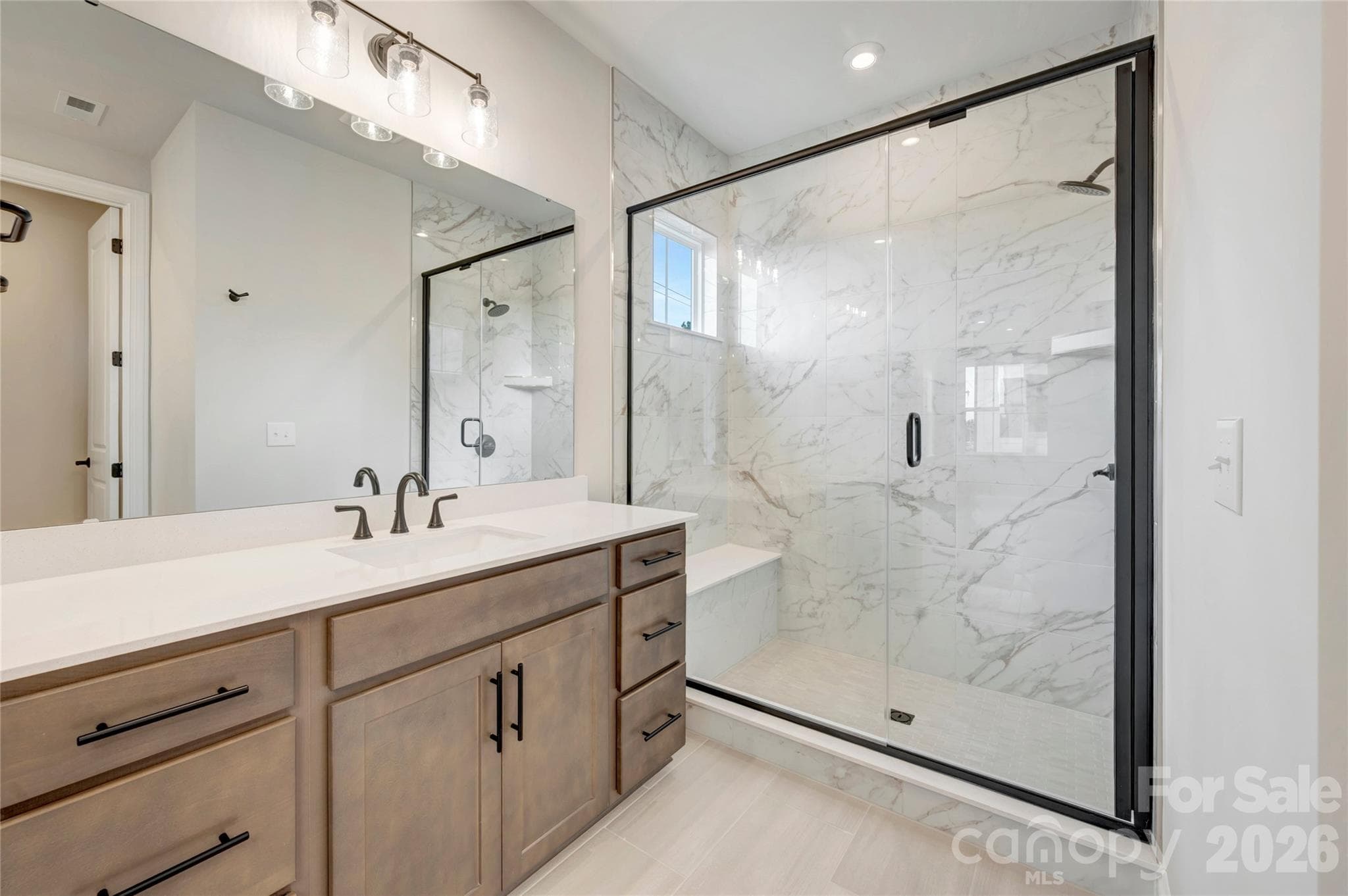 Dual vanity primary bathroom with tiled walk-in shower with a built-in seat - 13023 Lucy Park Lane, Charlotte