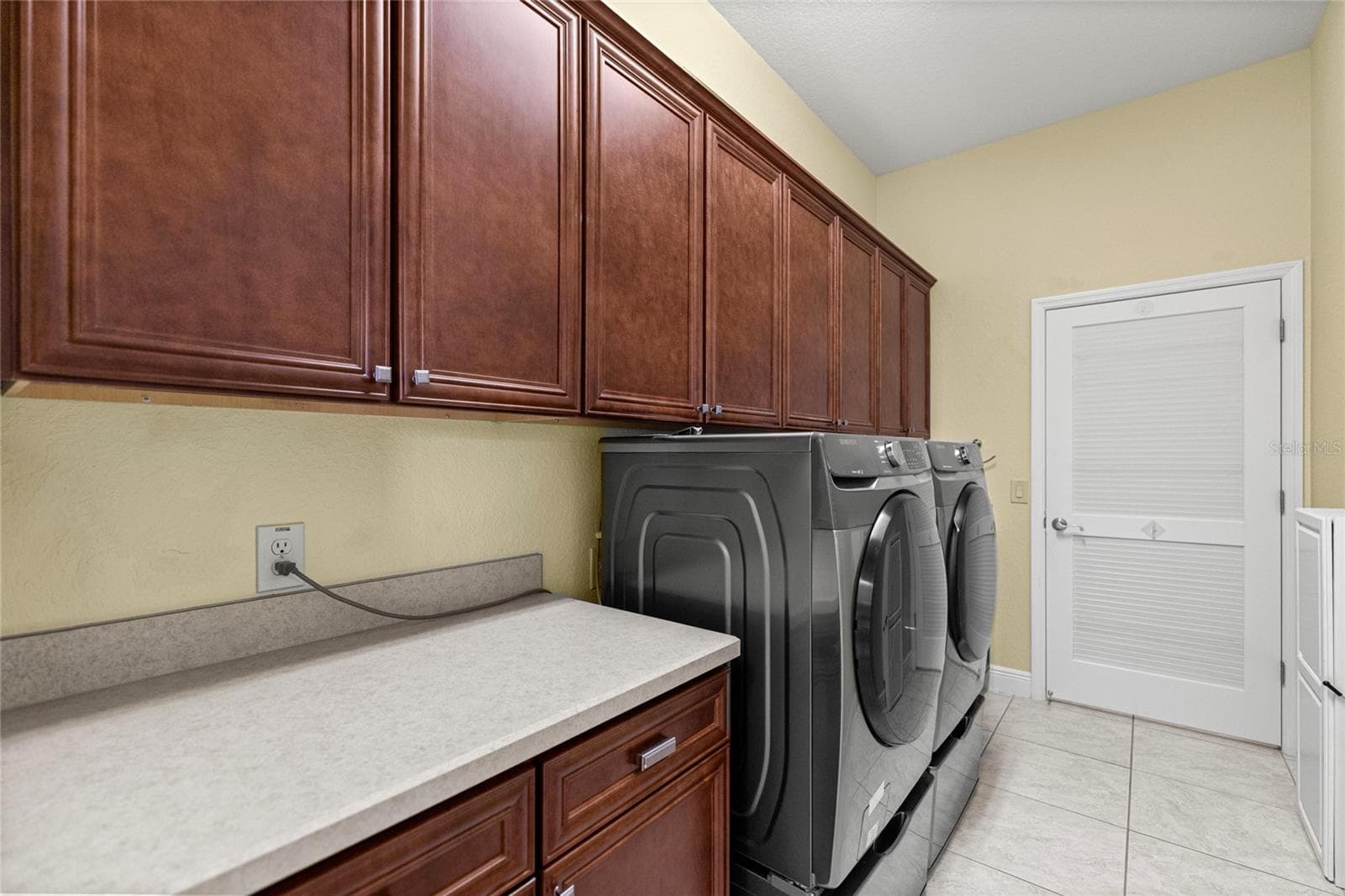 Indoor Laundry Room with Custom Cabinetry, Utility Sink, and Folding Counter. - 1126 MIONA SHORES DR, THE VILLAGES