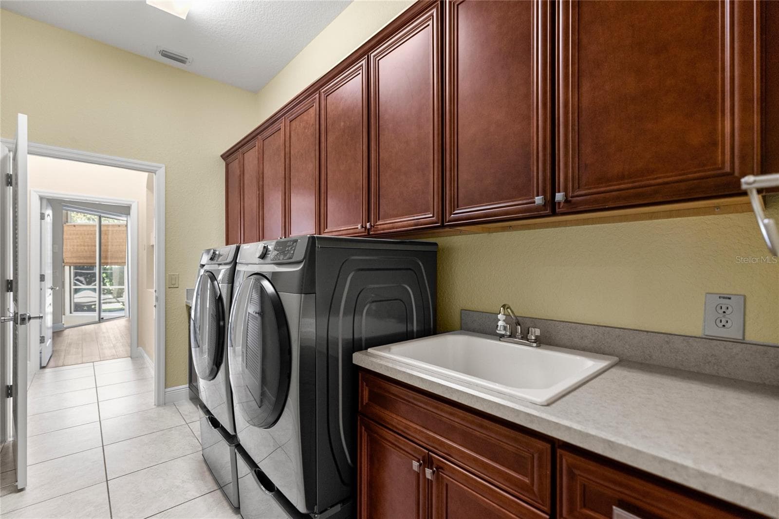 Indoor Laundry Room with Custom Cabinetry, Utility Sink, and Folding Counter. - 1126 MIONA SHORES DR, THE VILLAGES