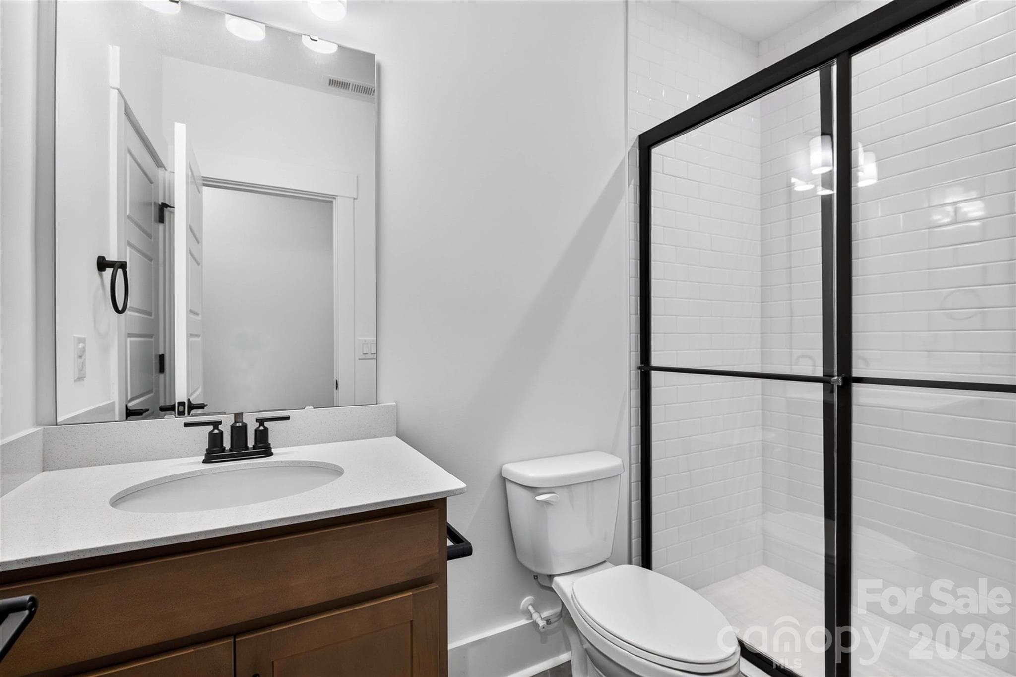 Even the basement bath gets the full treatment. A clean walk-in shower with black-frame glass because the details should never stop at the main floor. - 1216 Glade Arch Lane, Huntersville
