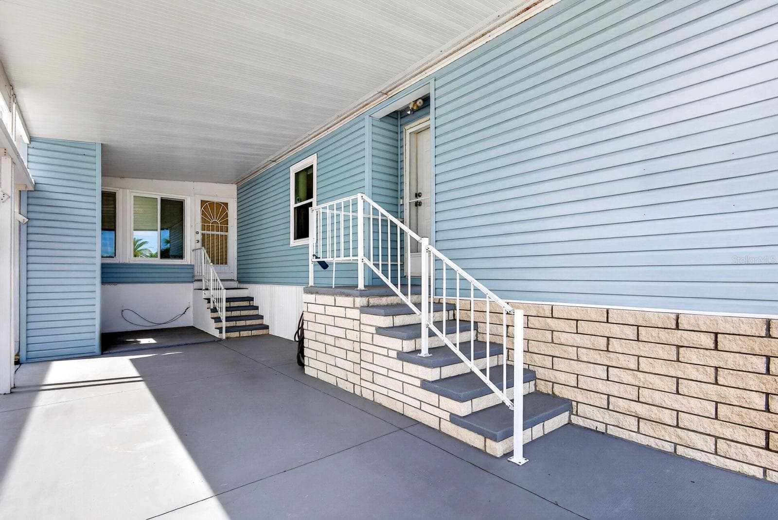 Carport with two entrances one into living area on the right and the other into enclosed lanai sunroom - 10315 CORTEZ RD W #7F, BRADENTON