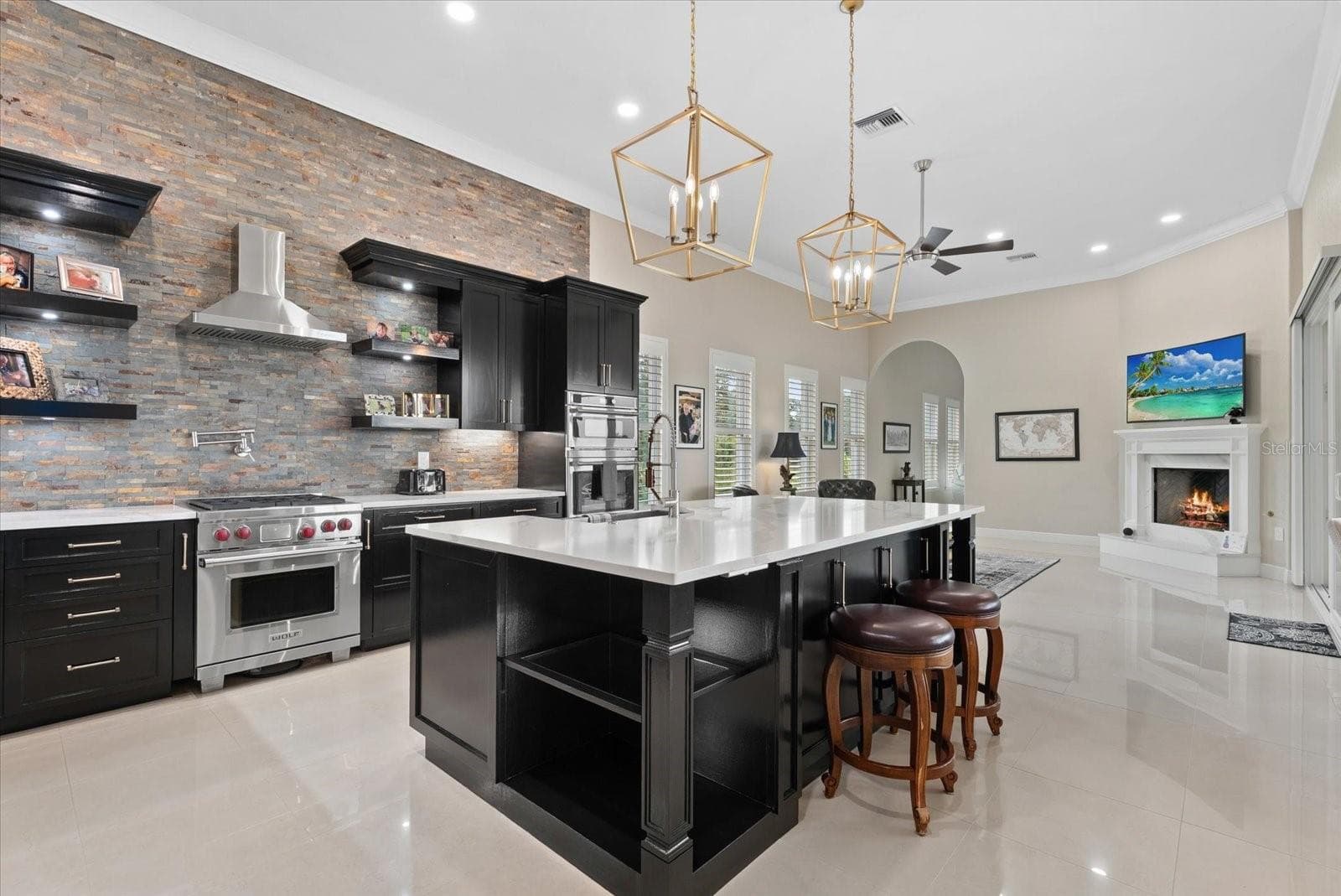 The chefs kitchen features new cabinets, a stone backsplash, pot filler over the gas stove, a large island, and a view into the family room - 520 RYE RD NE, BRADENTON