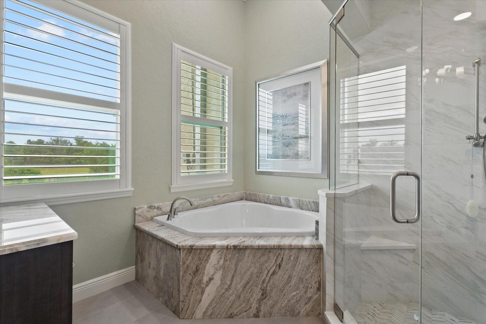 A step in shower and deep garden tub are tucked into the corner of the ensuite bath of the primary suite - 520 RYE RD NE, BRADENTON