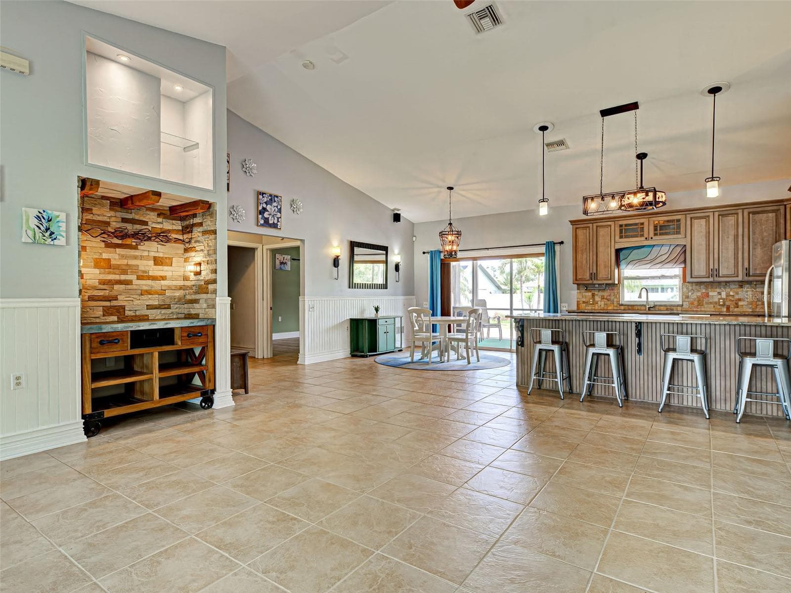 The dining area is steps away from the kitchen and has access to the lanai through the sliding glass doors. Look at the beautiful light fixtures. - 23102 MADELYN AVE, PORT CHARLOTTE