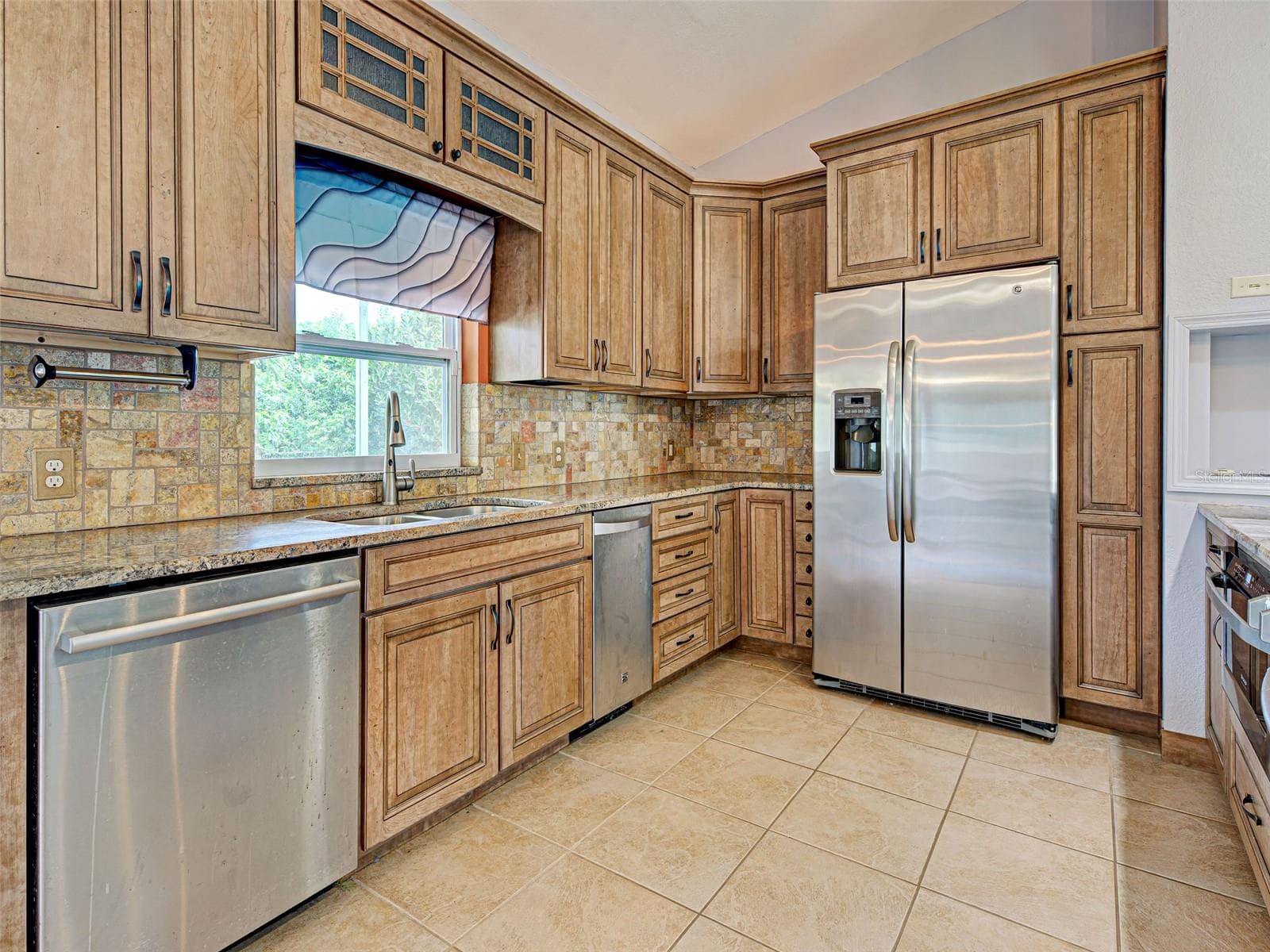 The backsplash blends in perfectly with the stone countertops. - 23102 MADELYN AVE, PORT CHARLOTTE