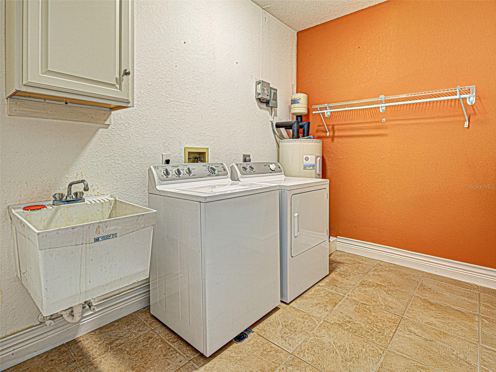 The laundry room has a storage cabinet on the wall and a wash tub. - 23102 MADELYN AVE, PORT CHARLOTTE