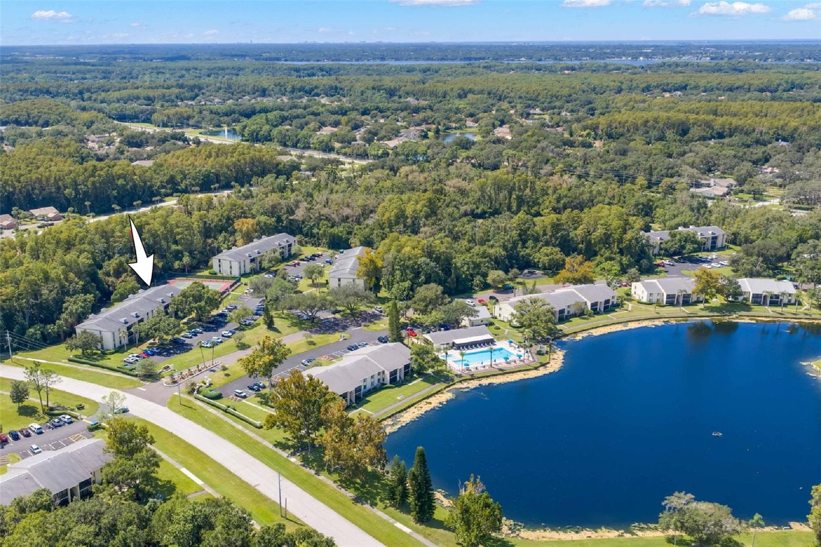 The arrow shows Building 218 within the community, with the pool, clubhouse, lake, and surrounding green space all close by. - 3188 LAKE PINE WAY S #F1, TARPON SPRINGS
