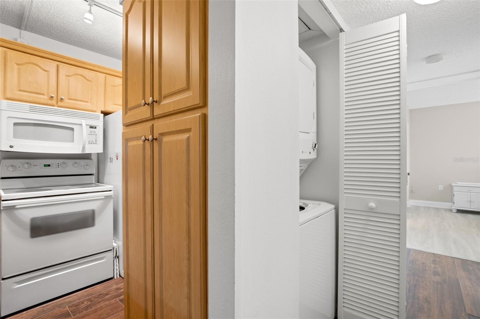 A dedicated laundry closet just off the kitchen keeps the stacked washer and dryer neatly tucked away, with additional built-in cabinetry close at hand. - 3188 LAKE PINE WAY S #F1, TARPON SPRINGS