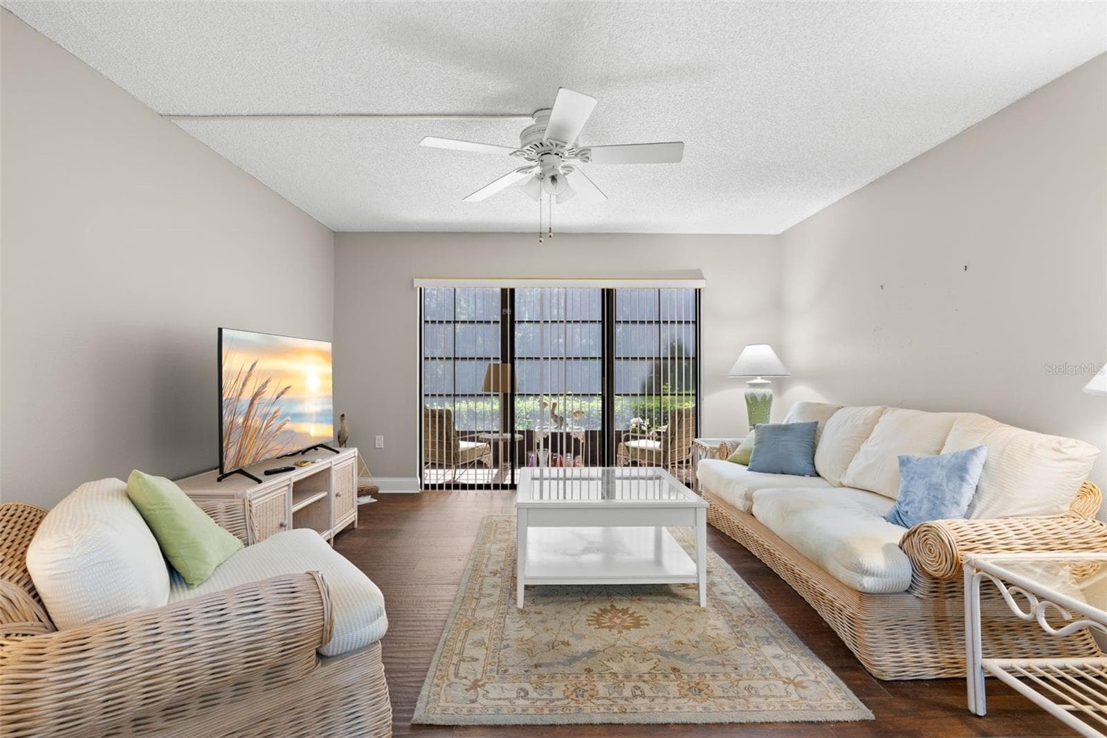 The living room is comfortably proportioned, with a wide bank of sliders extending the view toward the screened lanai and creating an easy indoor-outdoor connection. - 3188 LAKE PINE WAY S #F1, TARPON SPRINGS