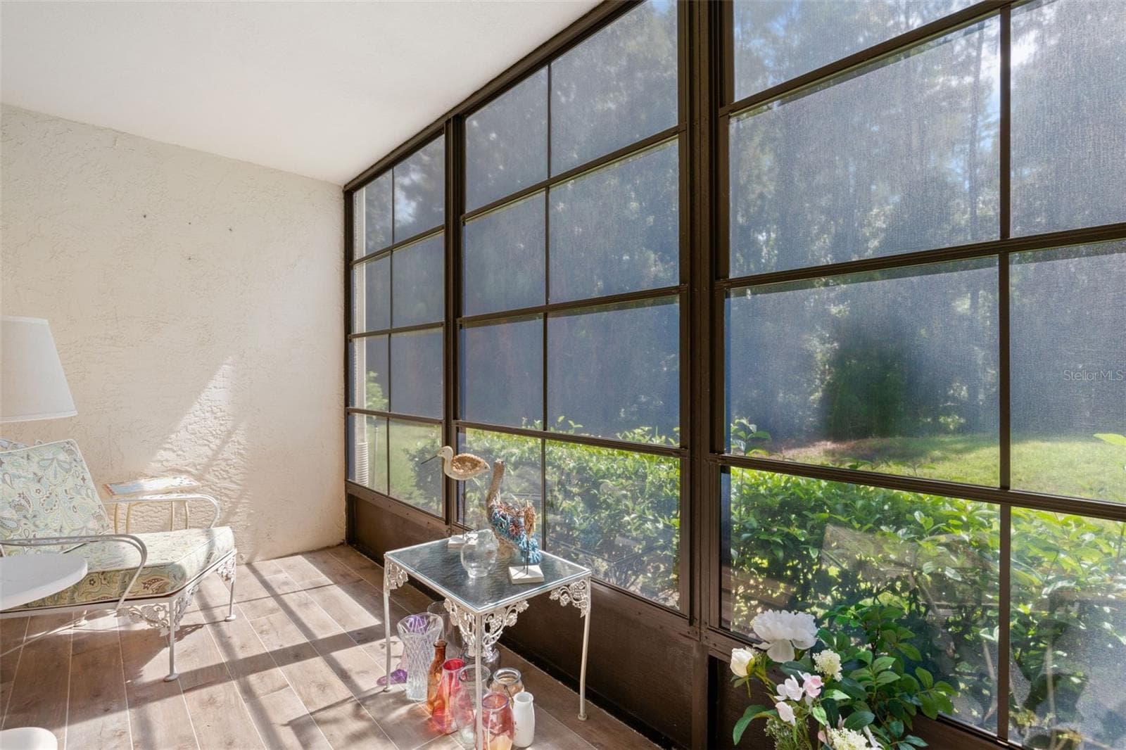 The screened lanai is wrapped in oversized screened windows, bringing in loads of natural light while framing the green, preserve-side setting just beyond. - 3188 LAKE PINE WAY S #F1, TARPON SPRINGS