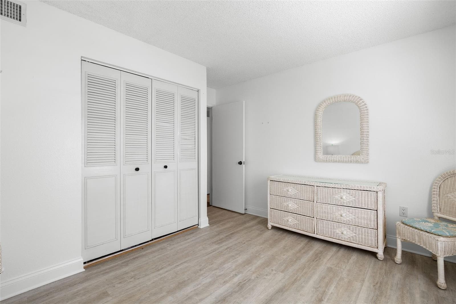 Louvered closet doors gives the second bedroom plenty of built-in storage, while the light flooring and neutral walls keep the room feeling open and flexible. - 3188 LAKE PINE WAY S #F1, TARPON SPRINGS