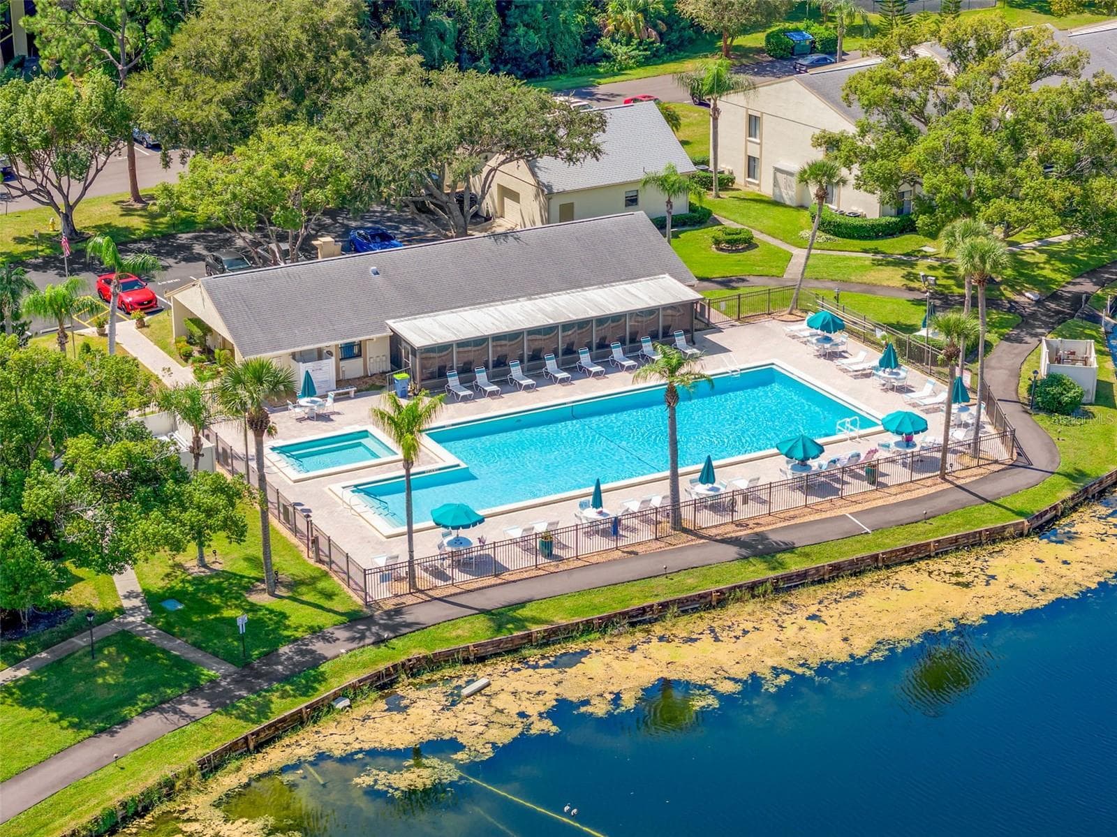 The lakeside recreation area features a heated community pool, jacuzzi, generous deck seating, and a clubhouse overlooking the water—a welcoming spot to swim, relax, or gather with friends. - 3188 LAKE PINE WAY S #F1, TARPON SPRINGS