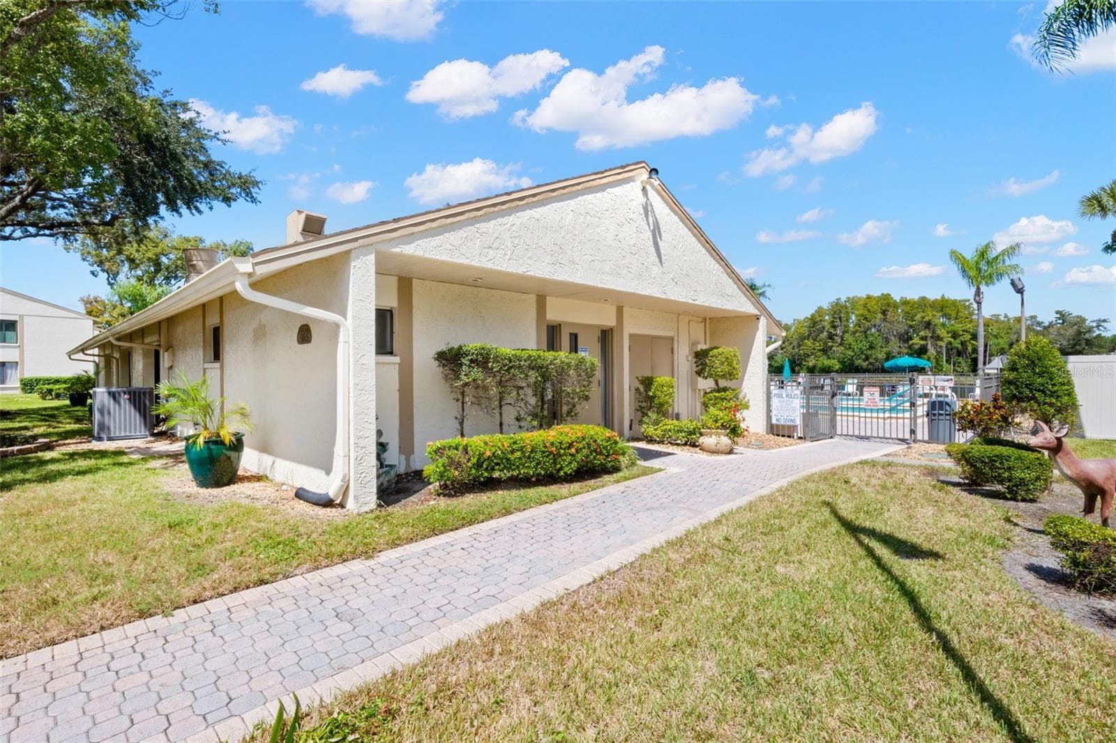 The clubhouse sits just steps from the pool, surrounded by landscaped grounds and paved walkways that make the community amenities easy to enjoy. - 3188 LAKE PINE WAY S #F1, TARPON SPRINGS