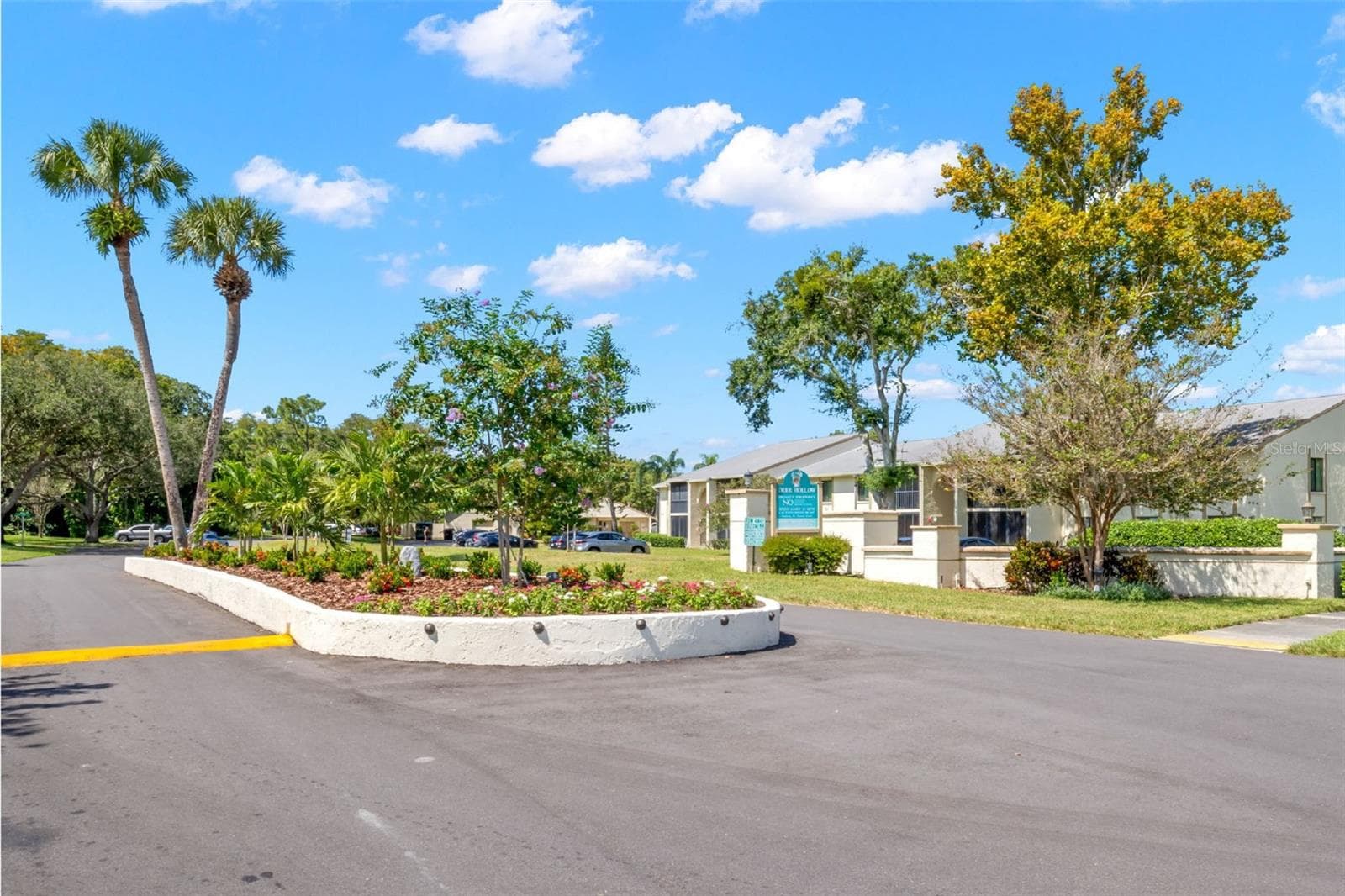 The landscaped entrance to Pine Ridge at Lake Tarpon features a flowering median, mature palms and trees, and a well-kept approach into the community. - 3188 LAKE PINE WAY S #F1, TARPON SPRINGS