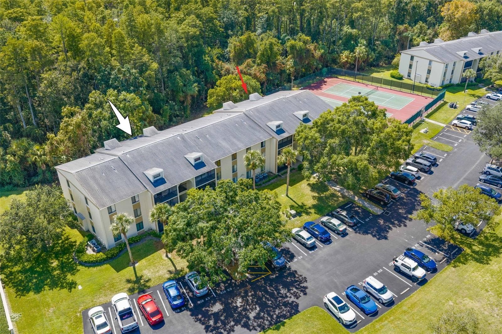 The arrow marks Unit F1’s first-floor location, with Brooker Creek Preserve directly behind the building, tennis courts just steps away, and parking conveniently located out front. - 3188 LAKE PINE WAY S #F1, TARPON SPRINGS
