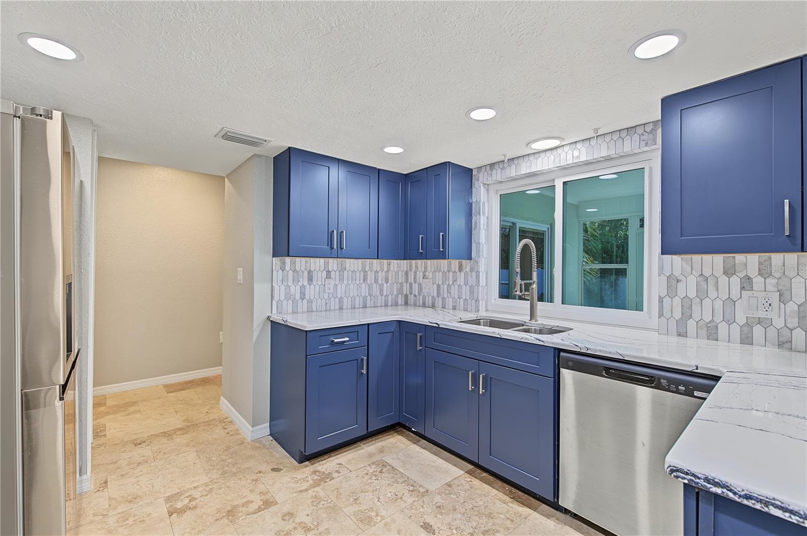 Beautifully designed kitchen featuring rich blue cabinetry, light countertops, and stainless steel appliances. - 260 SE 16TH TER, CRYSTAL RIVER