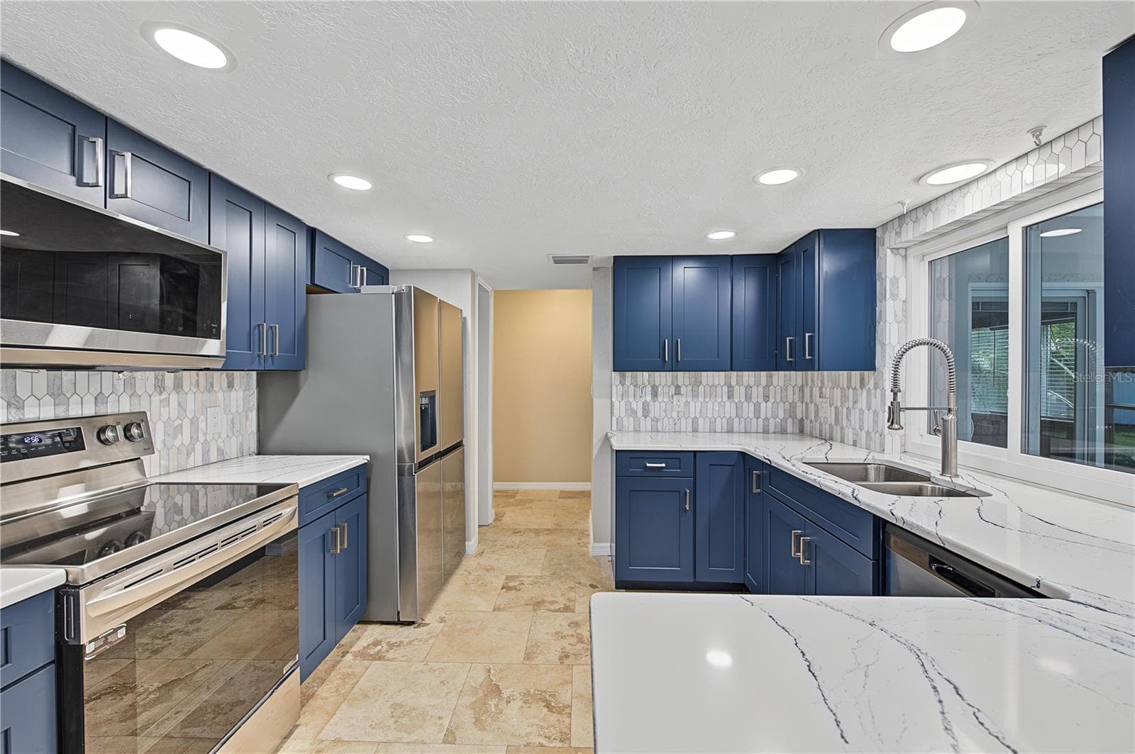 Another perspective of the kitchen showcasing stainless steel appliances, contemporary finishes, and ample workspace. - 260 SE 16TH TER, CRYSTAL RIVER