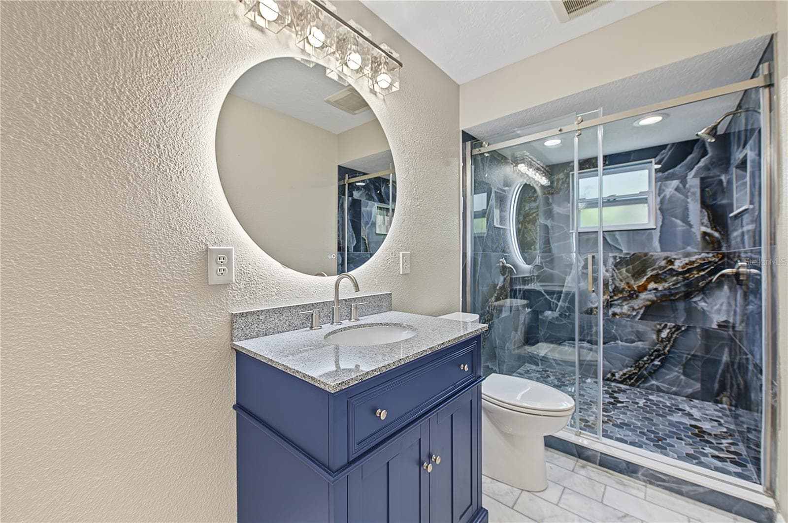 Modern vanity, round mirror, and glass-enclosed shower create a polished bathroom design. - 260 SE 16TH TER, CRYSTAL RIVER