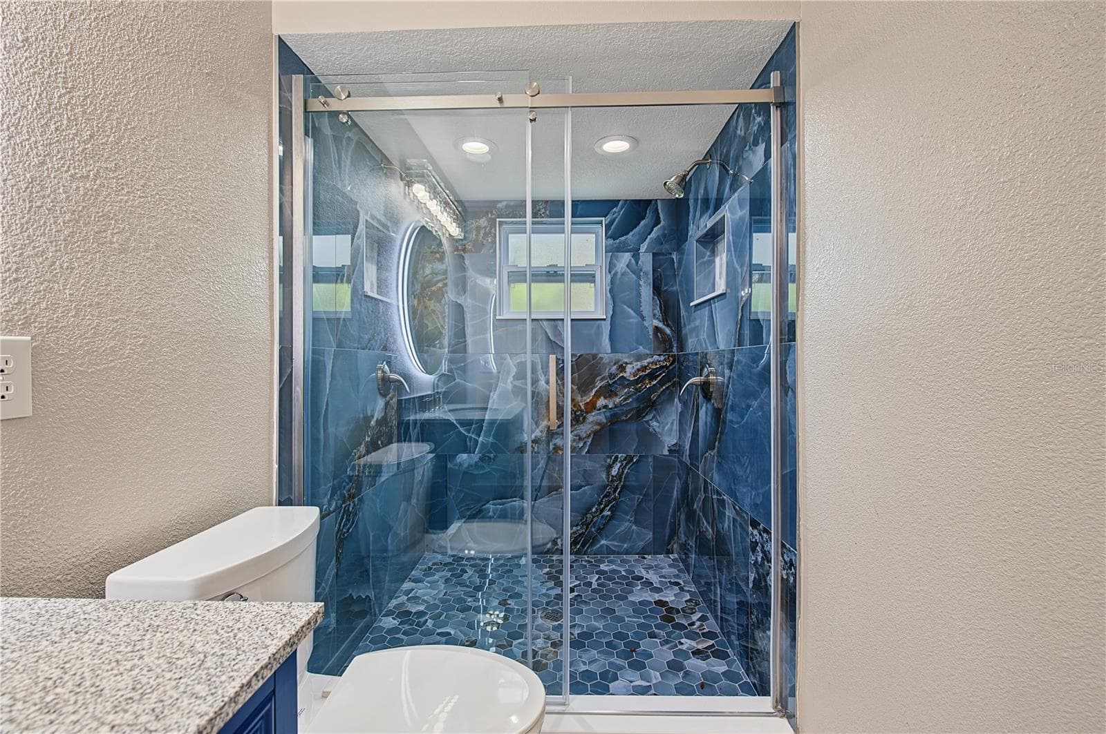 Contemporary bathroom featuring a glass-enclosed shower with distinctive blue tile accents. - 260 SE 16TH TER, CRYSTAL RIVER
