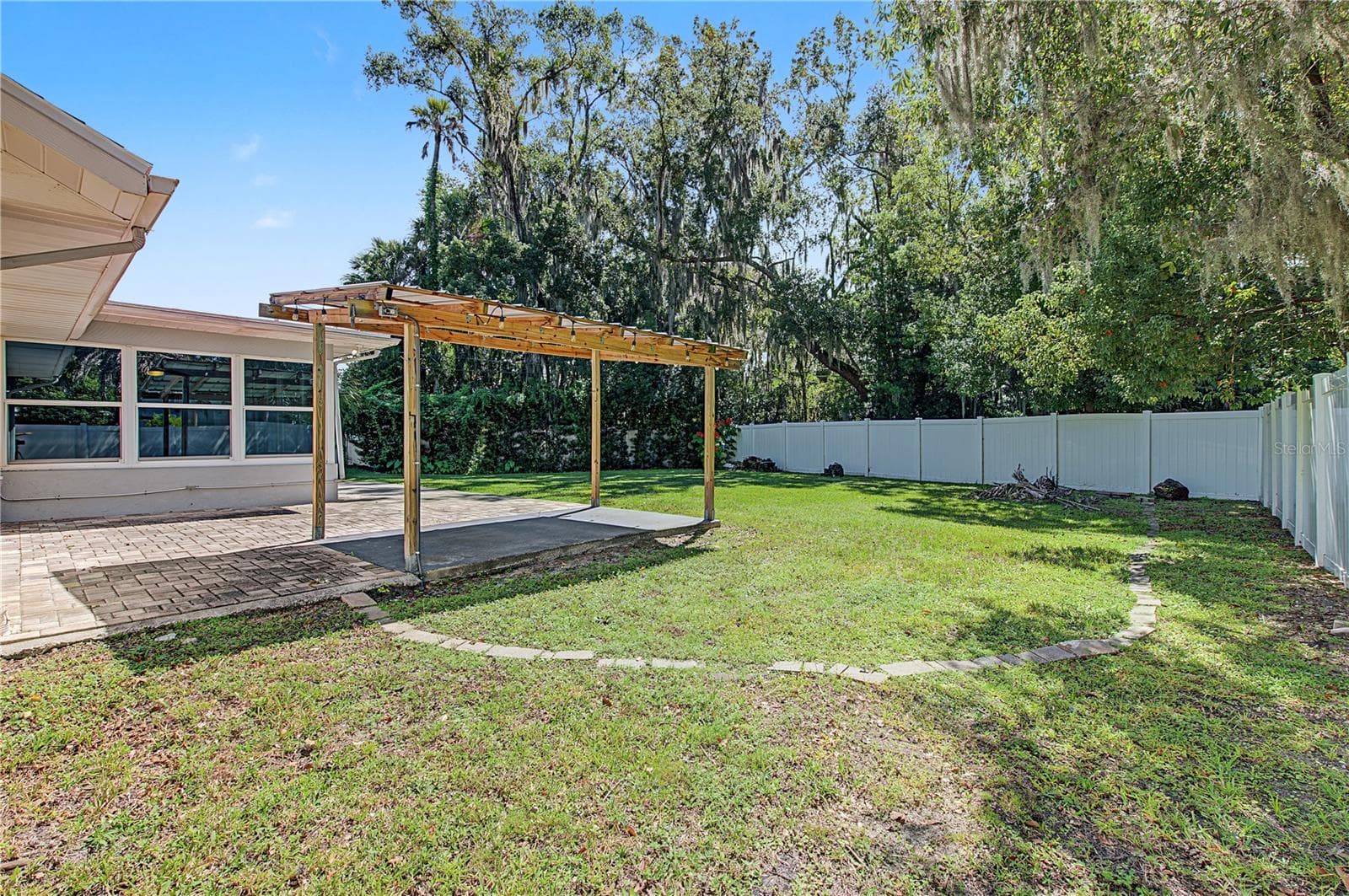 Expansive backyard with mature trees, open lawn, and a generous outdoor patio area. - 260 SE 16TH TER, CRYSTAL RIVER