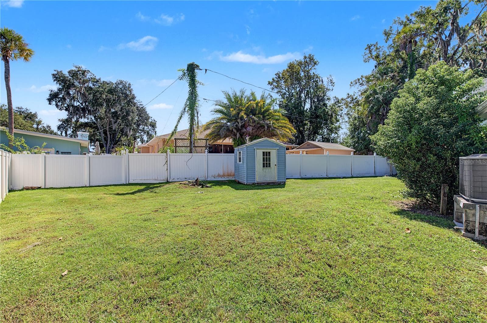 Open backyard with mature trees, fencing, and a detached storage shed. - 260 SE 16TH TER, CRYSTAL RIVER