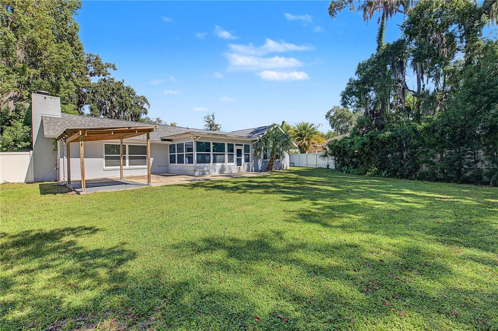 Spacious backyard offering a combination of open lawn, mature trees, and outdoor patio space. - 260 SE 16TH TER, CRYSTAL RIVER