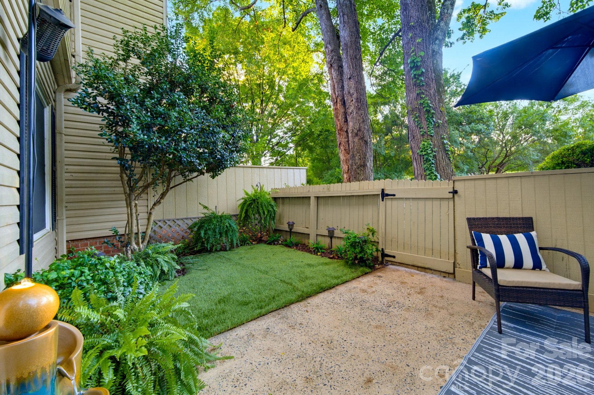 Enclosed outdoor living space with a charming picket fence and los-maintenance turf - ideal for pets, additional seating or dining, and plenty of room for your favorite plants. - 5901 Quail Hollow Road, Charlotte