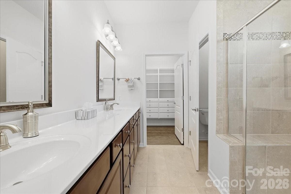 Primary bath showing double sinks, walk-in closet w/custom cabinets - 389 Harvest Valley Lane, Fort Mill