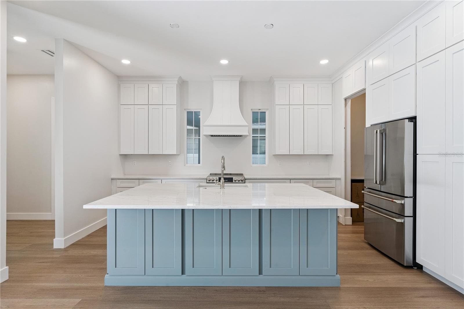 Main kitchen at 3456 Fairway Ln with a blue island, white counters, range hood, and stainless steel appliances. - 3456 FAIRWAY LN, ORLANDO