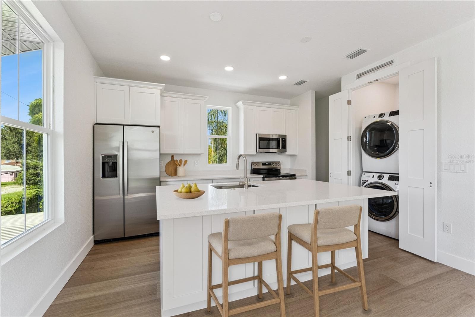Virtually Staged - The guest-suite kitchen includes a white island, stainless steel appliances, and a stacked washer and dryer. - 3456 FAIRWAY LN, ORLANDO