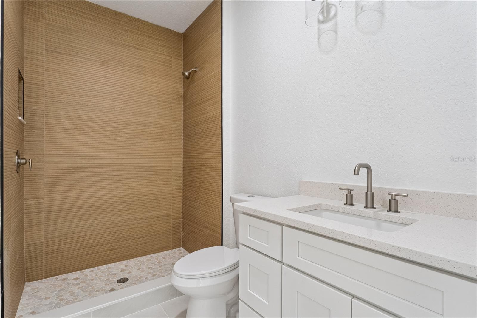 This bathroom features a white vanity and a walk-in shower with wood-look wall tile. - 3456 FAIRWAY LN, ORLANDO