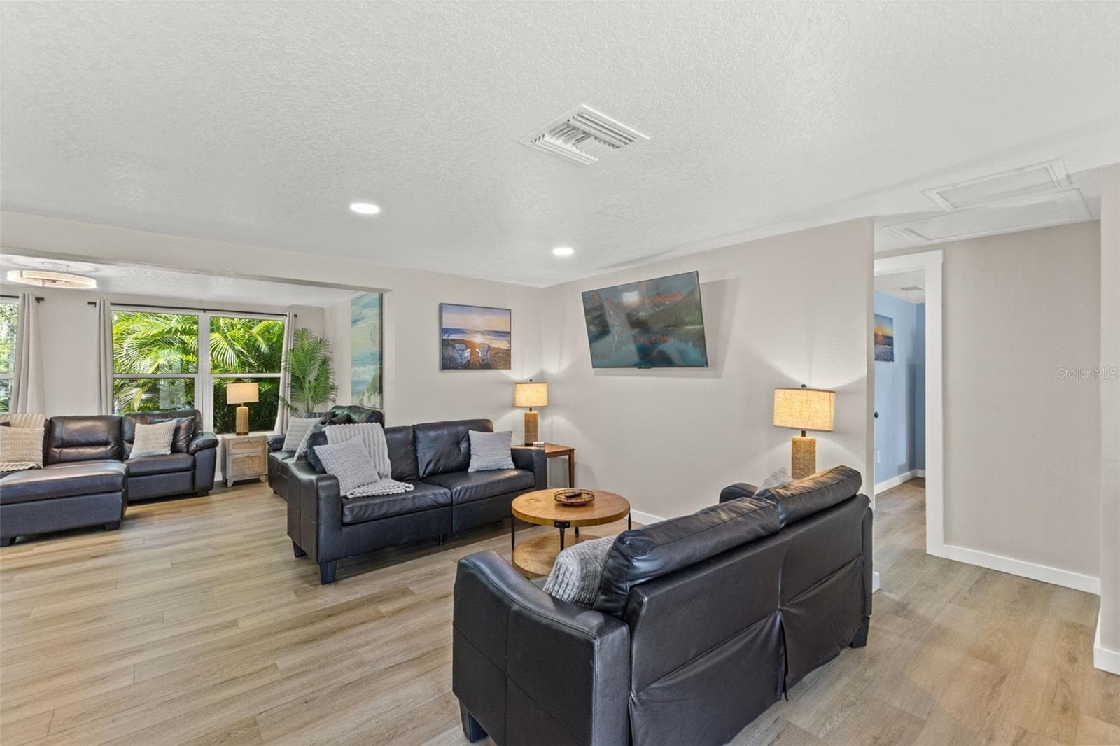 Spacious living area with luxury vinyl plank flooring, abundant natural light, and an open layout. - 201 SOUTH ST, PALM HARBOR