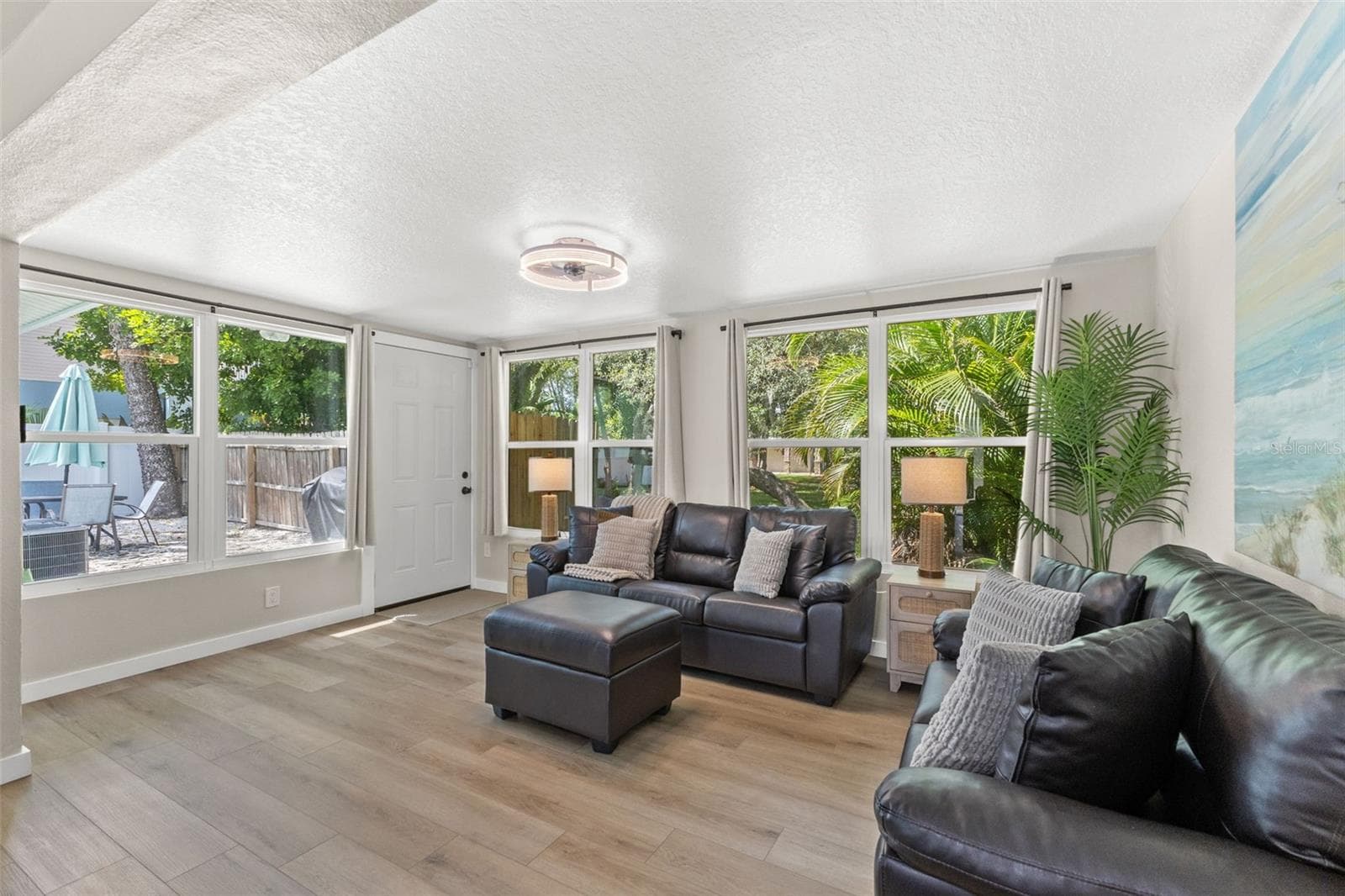 Multiple windows and direct outdoor access connect this bright living space to the home’s outdoor areas. - 201 SOUTH ST, PALM HARBOR