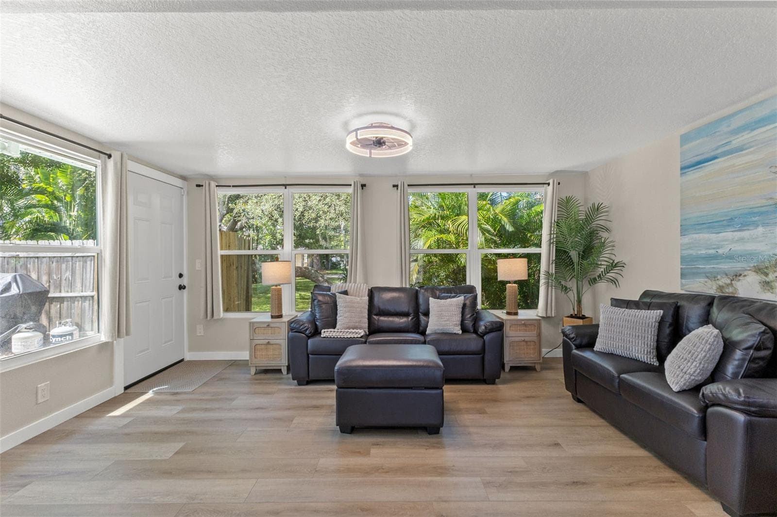 A wall of windows fills the room with natural light while overlooking the surrounding tropical landscaping. - 201 SOUTH ST, PALM HARBOR