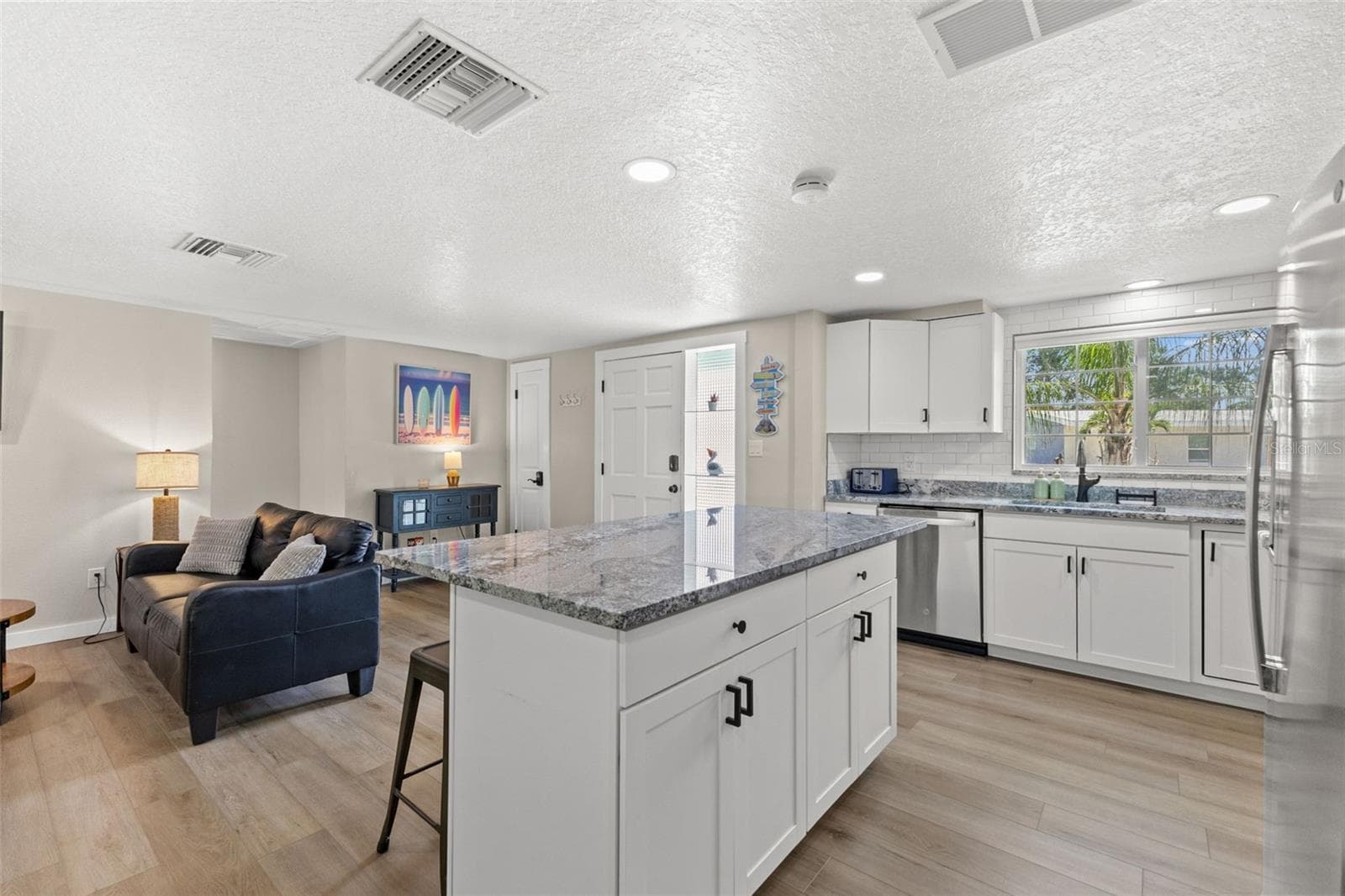 Generous granite-topped island adds abundant prep space, storage, and casual seating to the renovated kitchen. - 201 SOUTH ST, PALM HARBOR