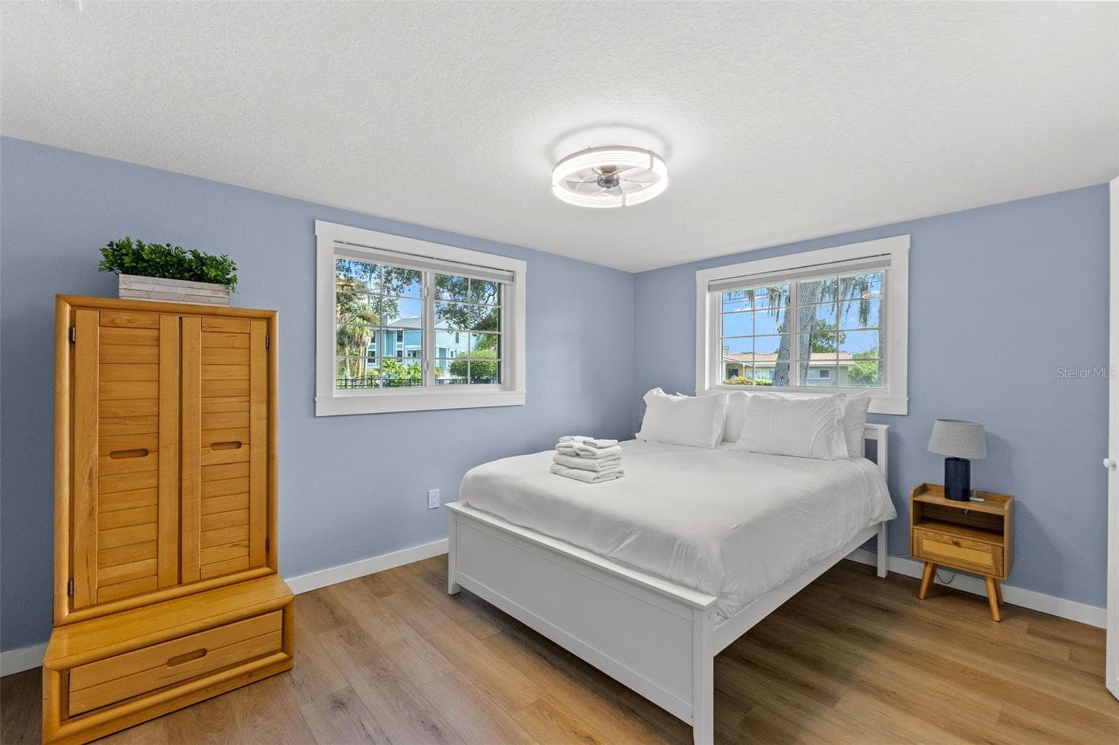 Bright bedroom with luxury vinyl plank flooring, two windows, and updated trim. - 201 SOUTH ST, PALM HARBOR