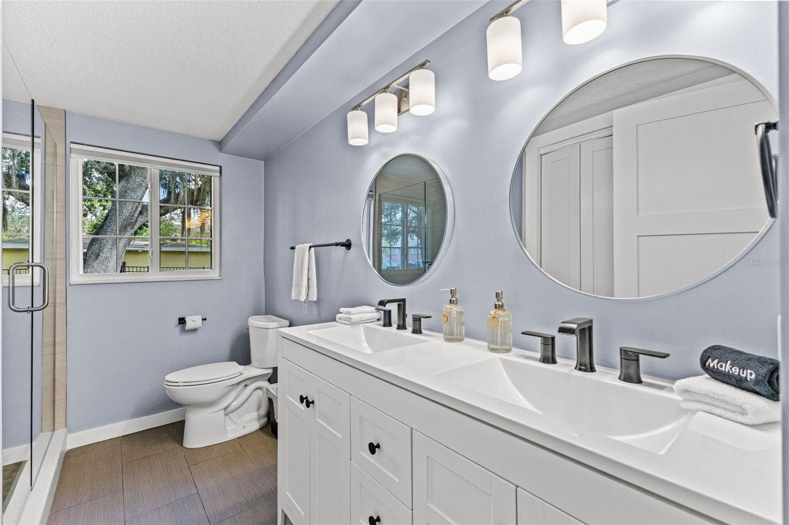 Updated bathroom with dual sinks, modern fixtures, generous vanity storage, and a glass-enclosed walk-in shower. - 201 SOUTH ST, PALM HARBOR