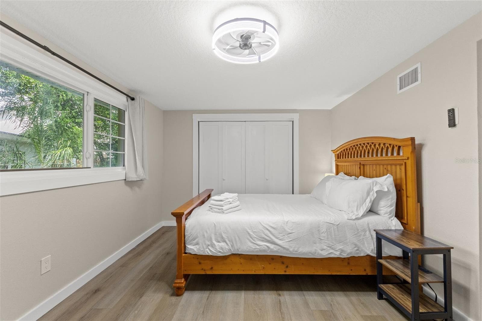 Bright secondary bedroom with luxury vinyl plank flooring, a large window, and ample closet storage. - 201 SOUTH ST, PALM HARBOR