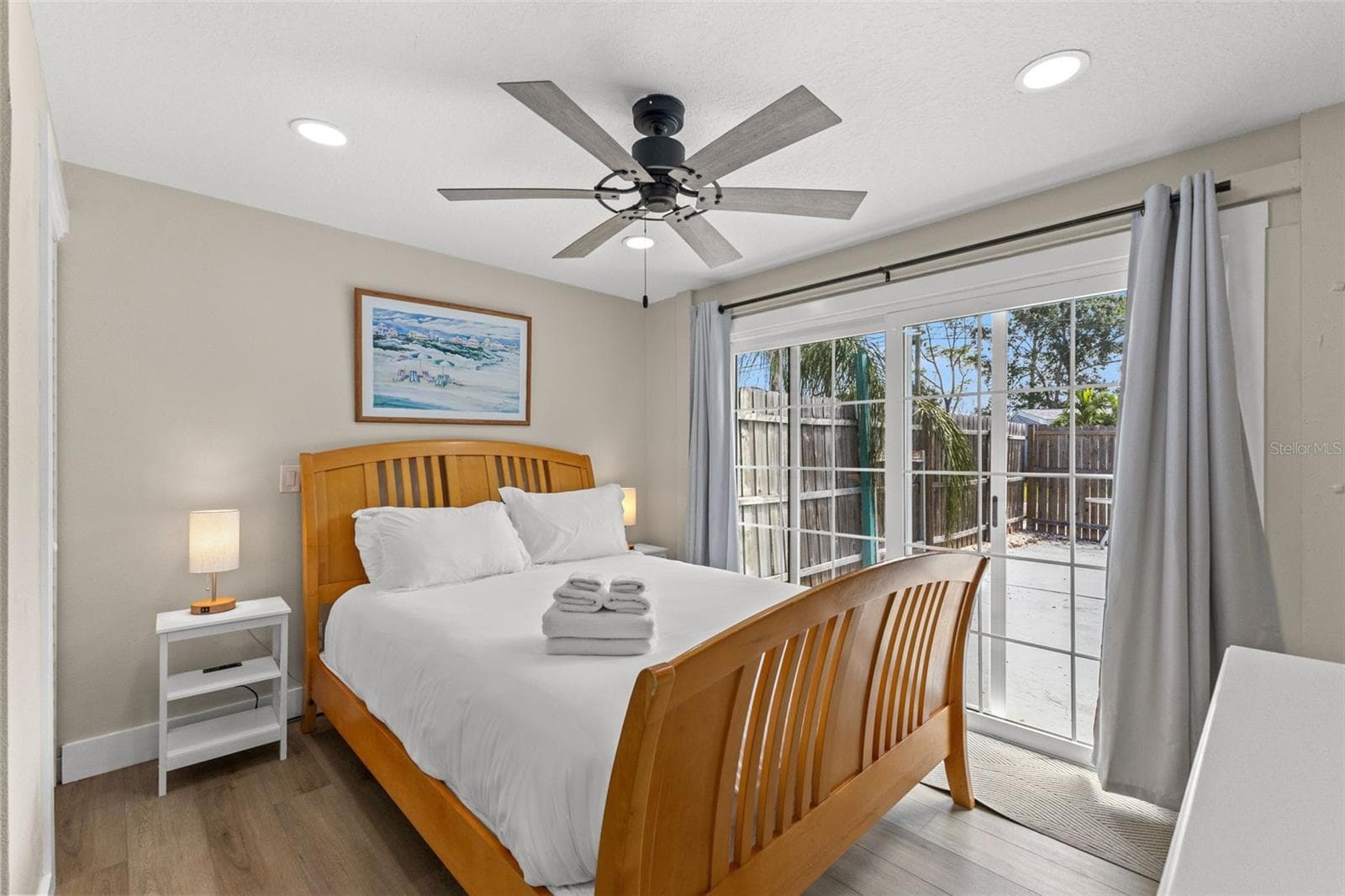 Owner's edroom with luxury vinyl plank flooring, ceiling fan, and sliding glass doors opening directly to the pool area. - 201 SOUTH ST, PALM HARBOR